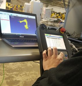 image of technician using a teach pendant and testing a robot